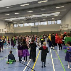 Carnival party in the gym with lots of children in colorful costumes.