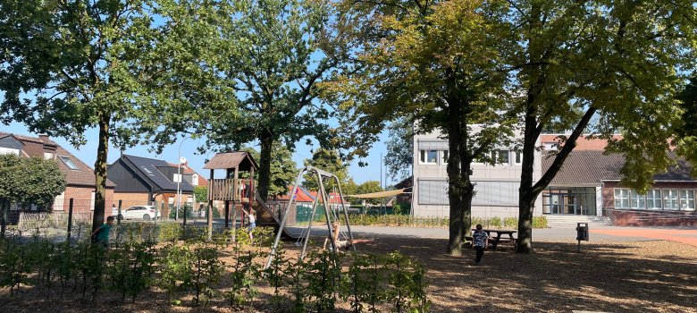 Cour d'école avec un toboggan et une balançoire.