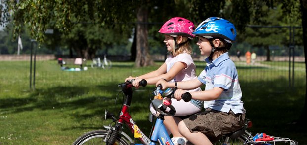 Divi bērni brauc ar velosipēdiem.