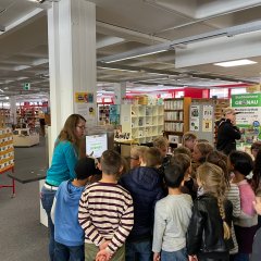 Die Mitarbeiterin gibt den Kindern eine Einführung in der Bücherei.