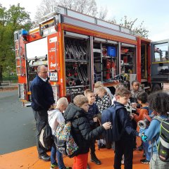 Feuerwehr mit einem Feuerwehrwagen auf dem Schulhof